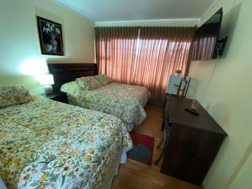 a hotel room with two beds and a desk at NEW HOTEL CRUZ DEL SUR in Concepción