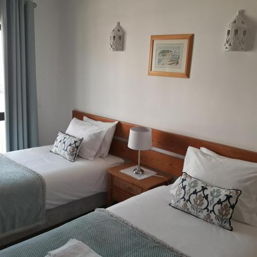 a hotel room with two beds and a lamp at Salema Beach Apartment in Salema