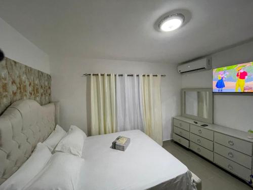 Schlafzimmer mit einem weißen Bett und einem TV in der Unterkunft Lujoso jacuzzi privado mi cell 347-864 -3082 in San Francisco de Macorís