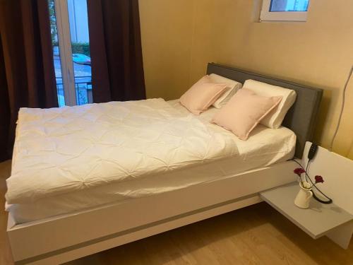 Bett mit weißer Bettwäsche und rosa Kissen in einem Zimmer in der Unterkunft Einliegerwohnung am Wald in Forbach