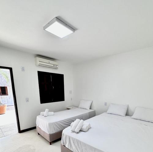 a white room with two beds and a television at Pousada VIGLAMO JERI in Jericoacoara