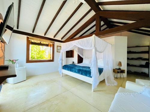 a bedroom with a bed with a mosquito net at Casa da Vila Outeiro das Brisas in Praia do Espelho