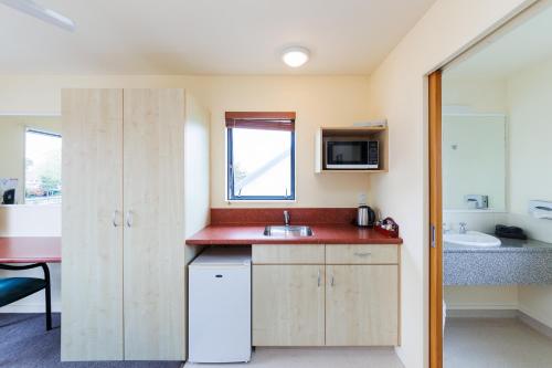 a small kitchen with a sink and a microwave at Bella Vista Motel Palmerston North in Palmerston North