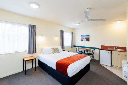 a hotel room with a bed and a kitchen at Bella Vista Motel Palmerston North in Palmerston North