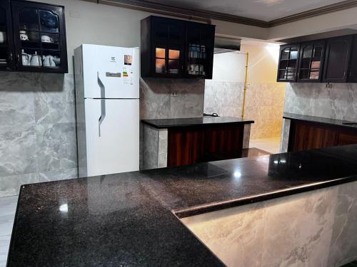 uma cozinha com um frigorífico branco e bancadas pretas em HOSTAL SAN MARCOS POTOSÍ em Potosí