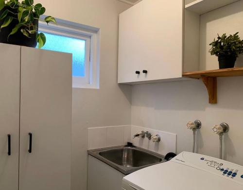 een keuken met een wastafel en een witte kast bij Pet friendly guesthouse with ping pong in Sydney
