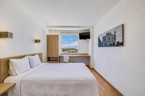 um quarto com uma cama branca e uma janela em One Leon Poliforum em León