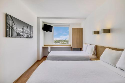 a hotel room with two beds and a tv at One Leon Poliforum in León