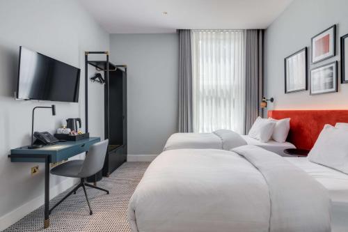 ロンドンにあるMornington Hotel London Kensington, BW Premier Collectionのベッド2台とデスクが備わるホテルルームです。
