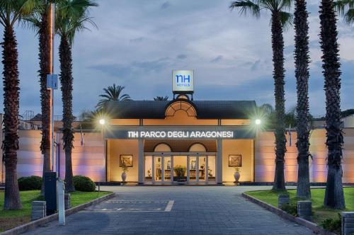 a hotel with palm trees in front of a building at NH Catania Parco degli Aragonesi in Catania