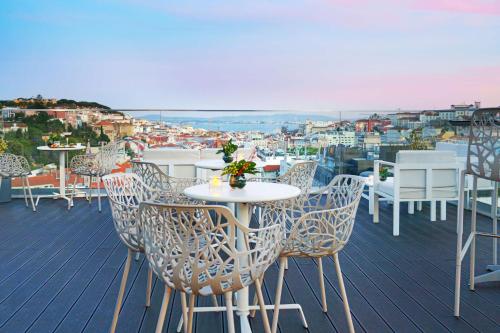 a balcony with tables and chairs and a view of a city at NH Collection Lisboa Liberdade in Lisbon