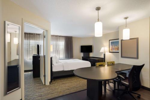 西德斯莫恩的住宿－Sonesta Simply Suites Des Moines，酒店客房设有一张床铺、一张桌子和一间卧室。