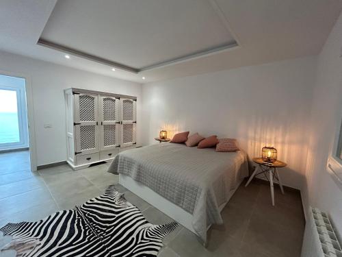 Dormitorio blanco con cama y alfombra de cebra en Casa Anna en Santa Úrsula