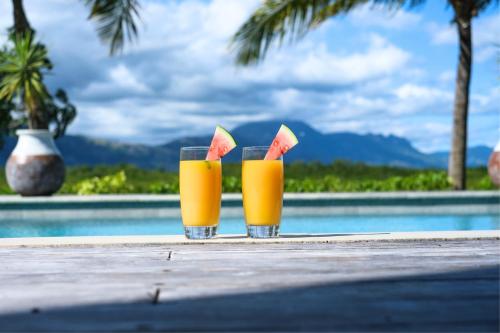 dos vasos de zumo de naranja con sandía en una mesa cerca de una piscina en Naisoso Island Villas - Fiji, en Nadi