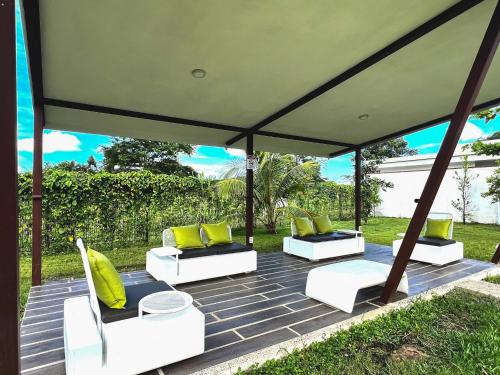 a gazebo with four white chairs and yellow pillows at Brand new apartment, minutes from the beach in Jacó