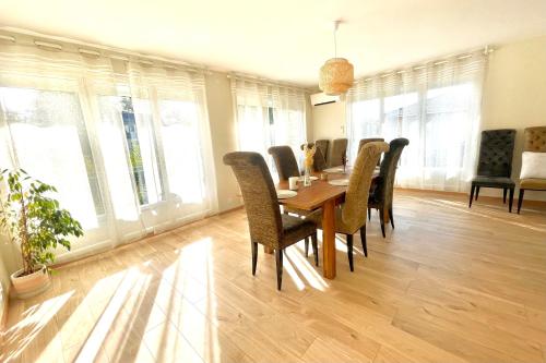 a dining room with a table and chairs and windows at VILLA EDOUARD - 180m2 in nature & forest - 20min Disney - 7min airport in Claye-Souilly