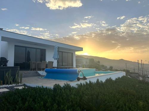 a house with a swimming pool with the sunset in the background at Villa Sundowner in Prazeres