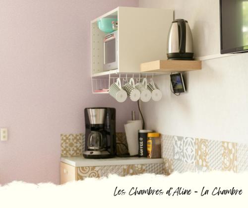 une cuisine avec une étagère, des tasses à café et un four micro-ondes dans l'établissement Les Chambres D'Aline, à Conches