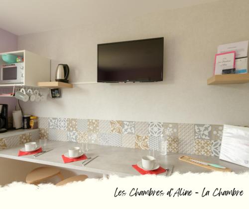 a room with a table with a tv on the wall at Les Chambres D'Aline in Conches