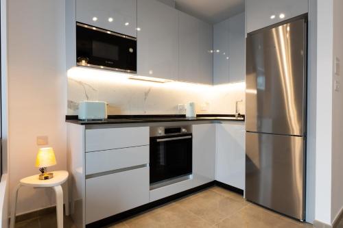 een keuken met witte kasten en een roestvrijstalen koelkast bij E1 Rock View Studio10 -Hosted by Sweetstay in Gibraltar
