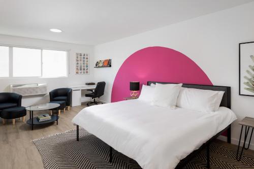 ロサンゼルスにあるFenix Hotel Hollywoodのピンクの壁のベッドルーム1室(大型ベッド1台付)