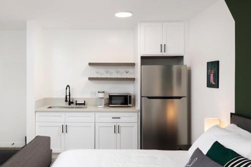 a kitchen with white cabinets and a stainless steel refrigerator at Fenix Hotel Hollywood in Los Angeles