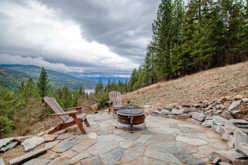 a patio with a grill and two chairs on a hill at Sagle Sunrise in Sagle