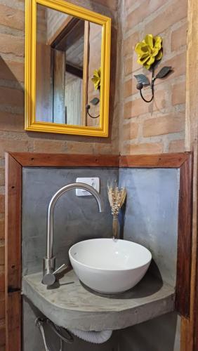 uma casa de banho com um lavatório branco e um espelho. em Pousada Aconchego do Caboclo em Sapucaí-Mirim