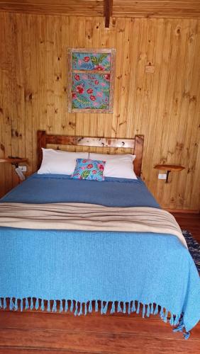 um quarto com uma cama com um cobertor azul em Pousada Aconchego do Caboclo em Sapucaí-Mirim