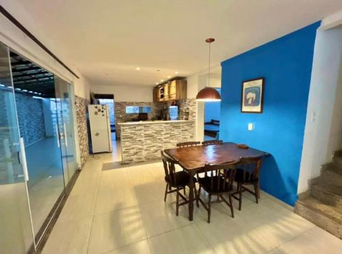 ein Esszimmer mit einem Holztisch und einer blauen Wand in der Unterkunft Casa Frente Praia Búzios in Búzios