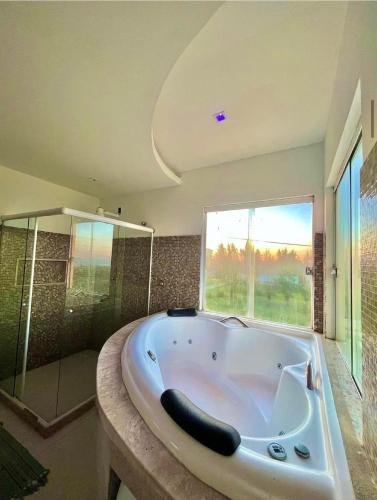 a large bath tub in a bathroom with a window at Casa Frente Praia Búzios in Búzios