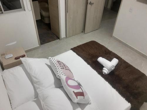 uma cama branca com almofadas e um edredão em Hermoso apartamento en sector exclusivo. em Bello
