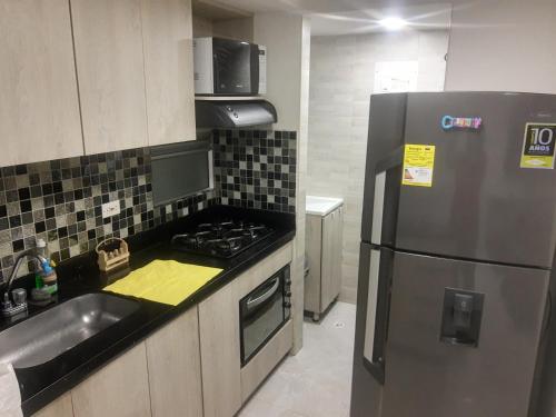 uma cozinha com um frigorífico de aço inoxidável e um lavatório em Hermoso apartamento en sector exclusivo. em Bello