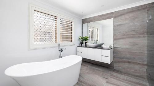 Un baño blanco con bañera y lavabo. en Coastal Breezes, en Corlette