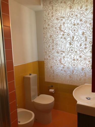 a bathroom with a toilet and a wallpaper at Mar-Vada Apartment Relax at the Tuscany coast in Vada