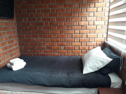 a bed against a brick wall with pillows on it at Onkel Inn Wagon Sleepbox Uyuni in Uyuni
