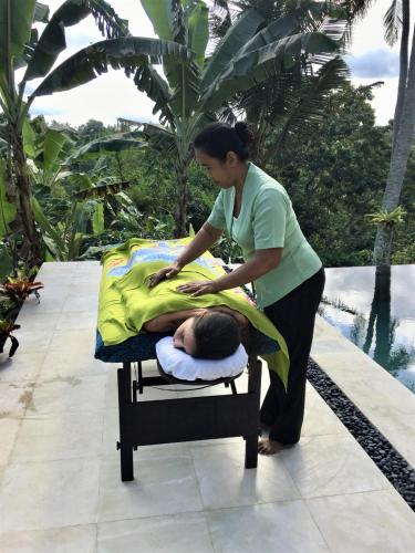 a woman is wrapping a child on a bed at Wake in Paradise and Luxury Lebah Villas in Ubud