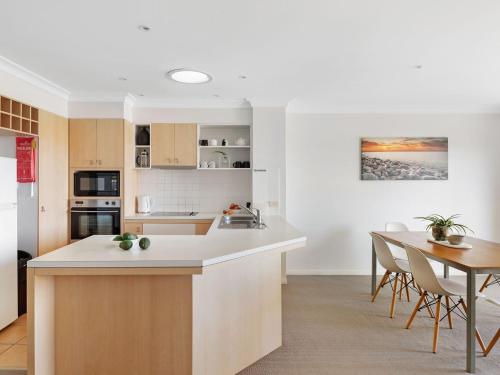 a kitchen and dining room with a table and chairs at Villa 51 - The Sands Resort in Yamba