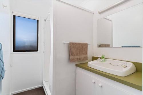 a white bathroom with a sink and a mirror at Wander into Wanaka in Wanaka