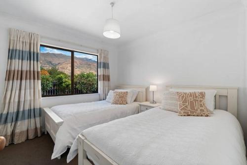 two beds in a bedroom with a large window at Wander into Wanaka in Wanaka