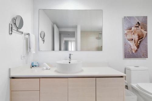 ein weißes Badezimmer mit einem Waschbecken und einem Spiegel in der Unterkunft Panoramic views 1 bed Beach Walk 27th Miami in Hollywood