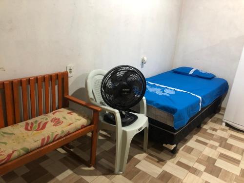 a room with a fan and a bed and a chair at Kitnet- Edícula em Fazendinha in Macapá