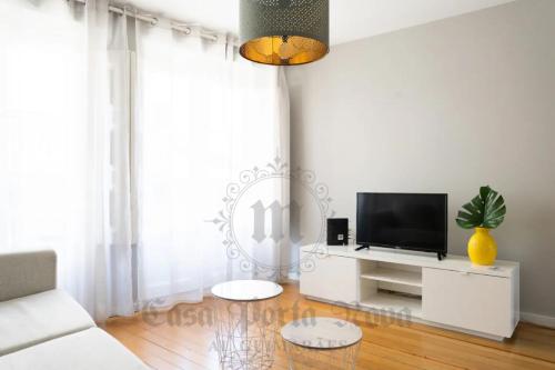 a living room with a white couch and a tv at Casa Porta Nova AL in Guimarães