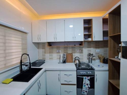 eine Küche mit weißen Schränken und einem Herd mit Backofen in der Unterkunft The Palladium Apartments in Ebute Lekki