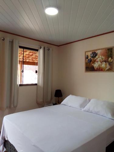 a bedroom with a white bed and a window at Hospedagem Frez in Nova Friburgo