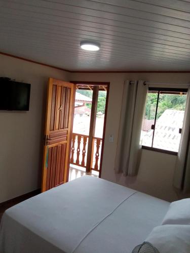 a bedroom with a bed and a view of a balcony at Hospedagem Frez in Nova Friburgo