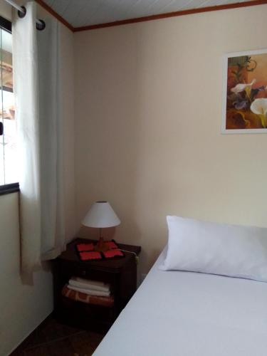 a bedroom with a white bed and a window at Hospedagem Frez in Nova Friburgo