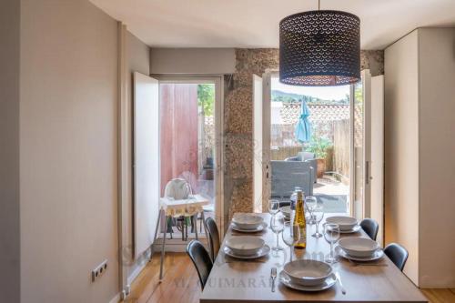 a dining room with a table and chairs and a room with a window at Casa Porta Nova AL in Guimarães