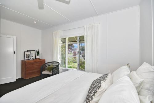 a white bedroom with a bed and a window at Coastal Escape in Long Jetty