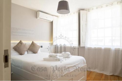 una camera bianca con un letto con lenzuola bianche e una finestra di Casa Porta Nova AL a Guimarães